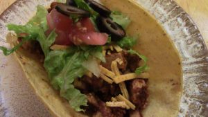 Tofu drenched in red chili sauce, and topped with vegan cheese, tomatoes, lettuce, and black olives.