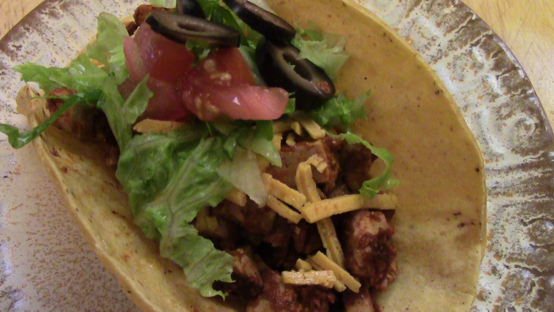 Tofu drenched in red chili sauce, and topped with vegan cheese, tomatoes, lettuce, and black olives.